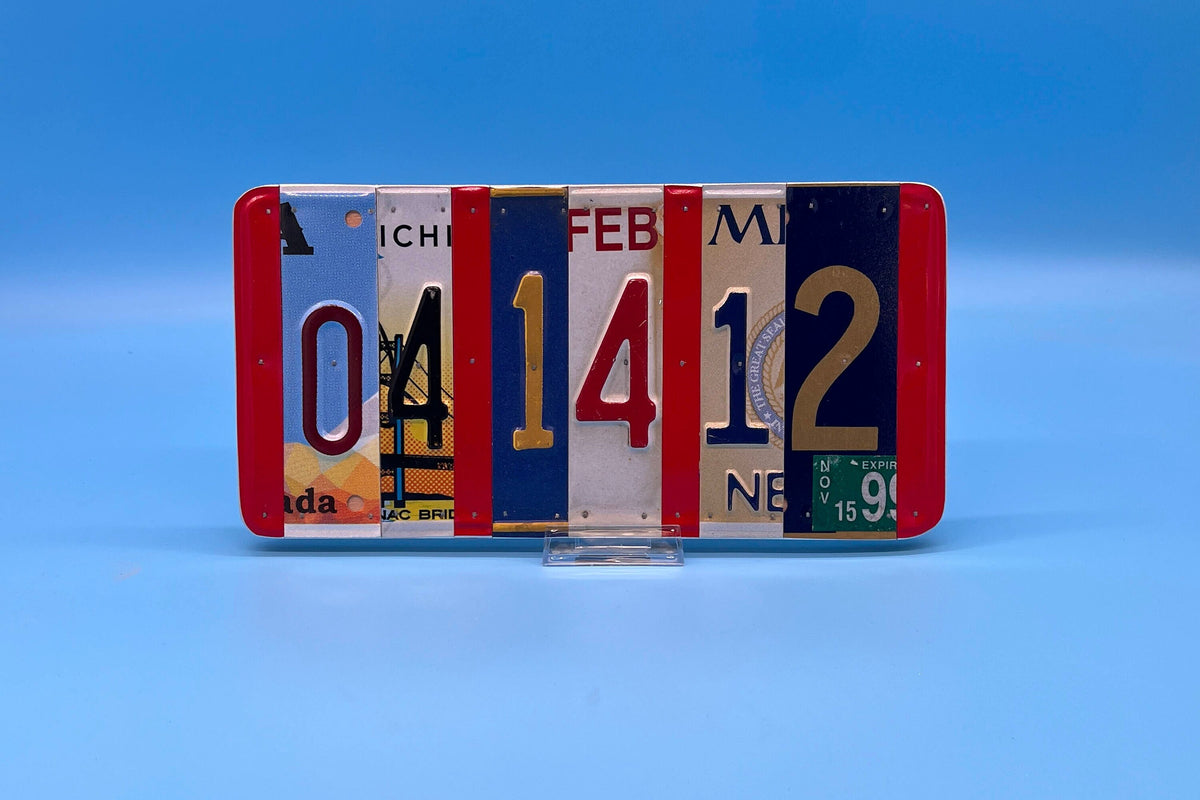 The numbers from recycled license plates. Cut into strips and nailed to wood. License plate numbers are from different states, very colorful and displayed on a blue background