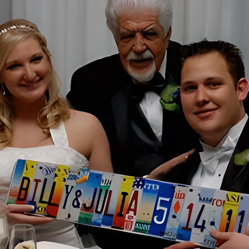 Three people in formal attire holding a license plate sign with 'BILLY & JULIA 5 14 11'. License plate letters cut and used to spell out whats on the sign.
