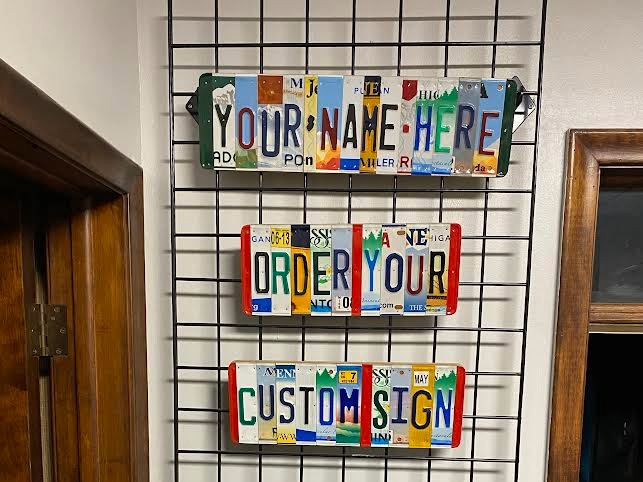 Decorative license plate art with customizable text on a wire rack.